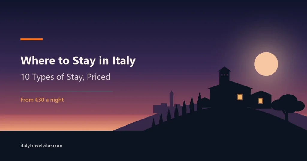 Where to stay in Italy cover: a stone farmhouse with lit windows at the end of a cypress avenue, in silhouette against a dusk sky